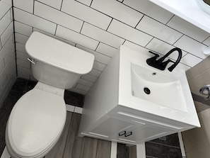 Bathroom features a toilet and sink mounted on a wall with a tile pattern.