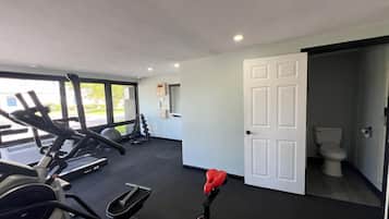 Una palestra con tapis roulant, cyclette e una rastrelliera per pesi.