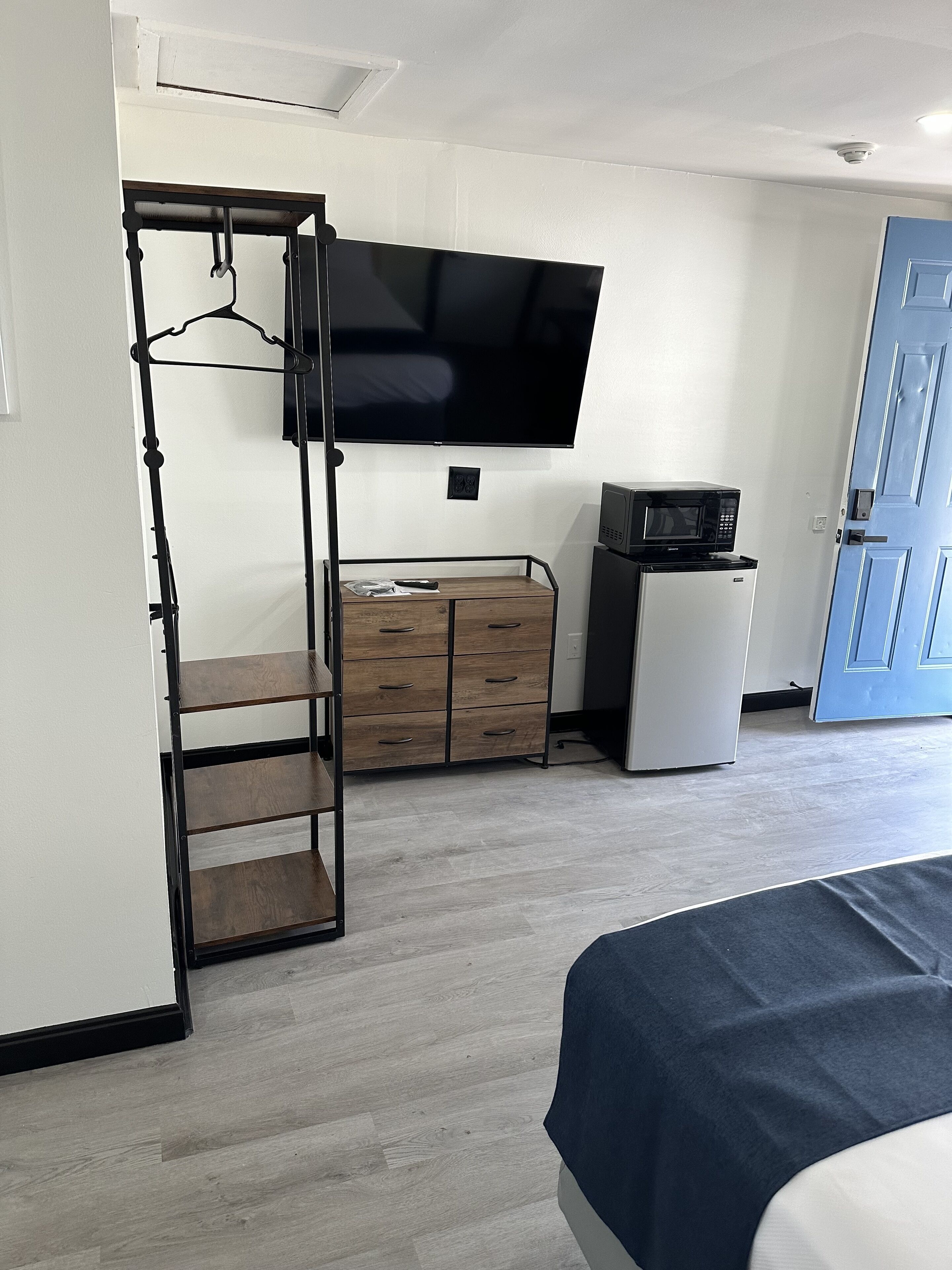 Ein Schlafzimmer mit Etagenbett, einem flachbildfernseher an der Wand, einer Mikrowelle, einem kleinen Kühlschrank und einer Kommode mit Schubladen.