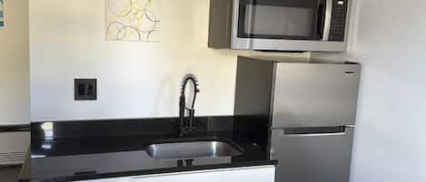 A compact kitchen with a built-in dishwasher, a microwave, and a refrigerator.