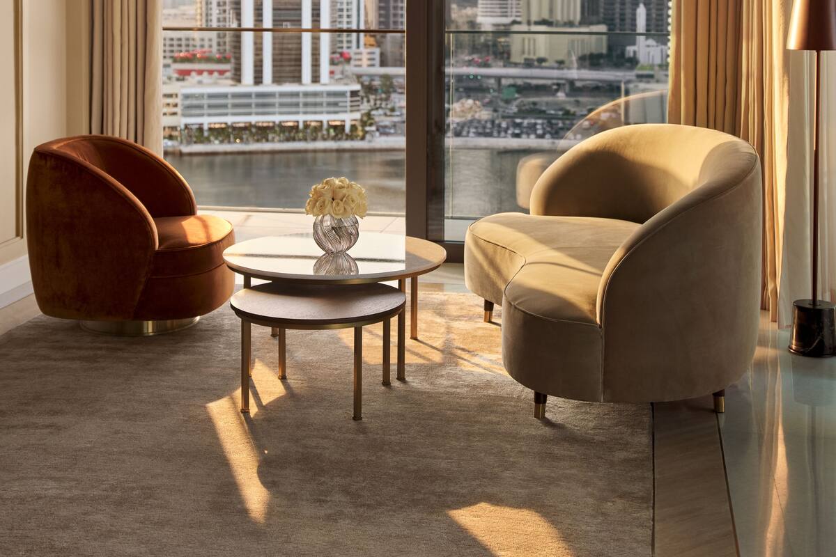 A modern living room with a large window, a round coffee table, a sofa, and a chair.