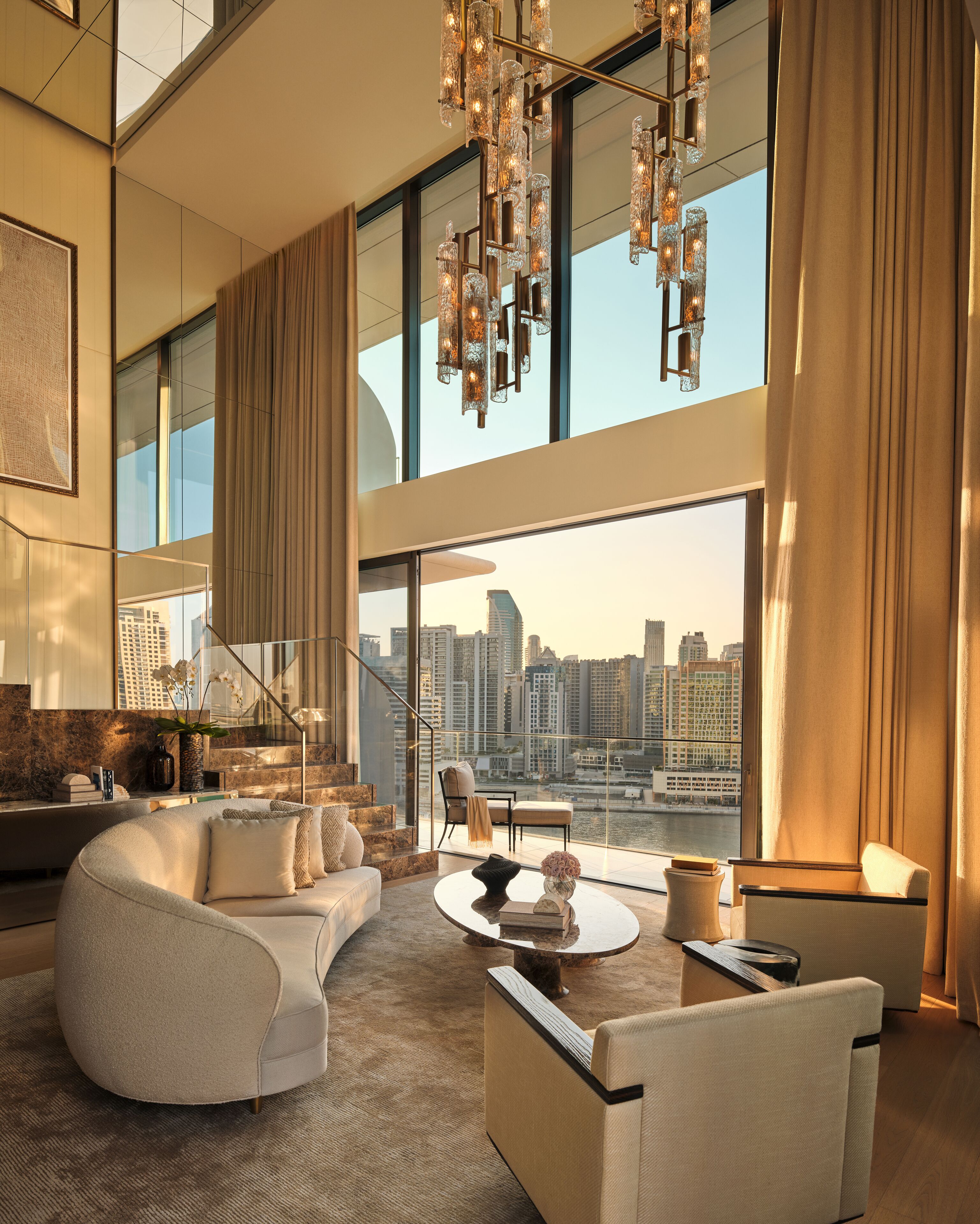 A modern living room with a city view, a large chandelier, and a spacious seating area.