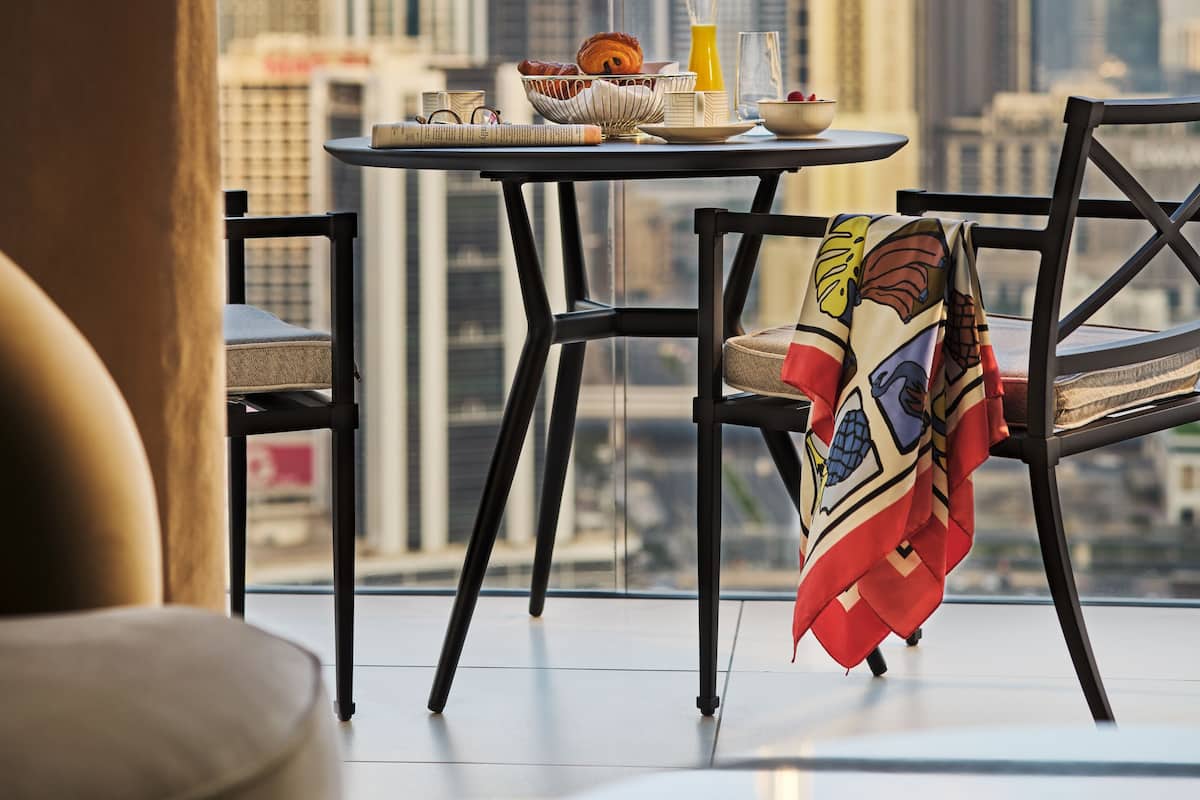 A balcony with a table set for breakfast, overlooking a cityscape with tall buildings.
