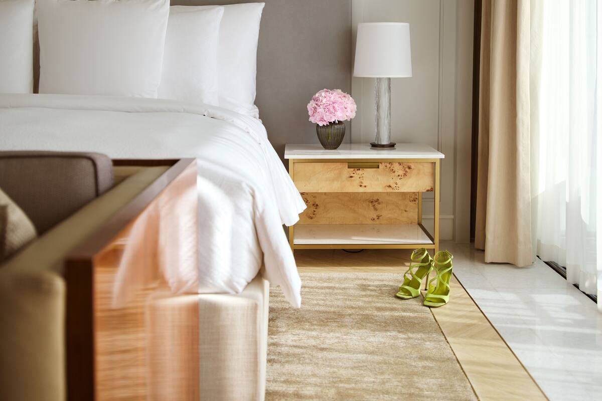 A bedroom with a bed, bedside table, lamp, and a window with curtains.