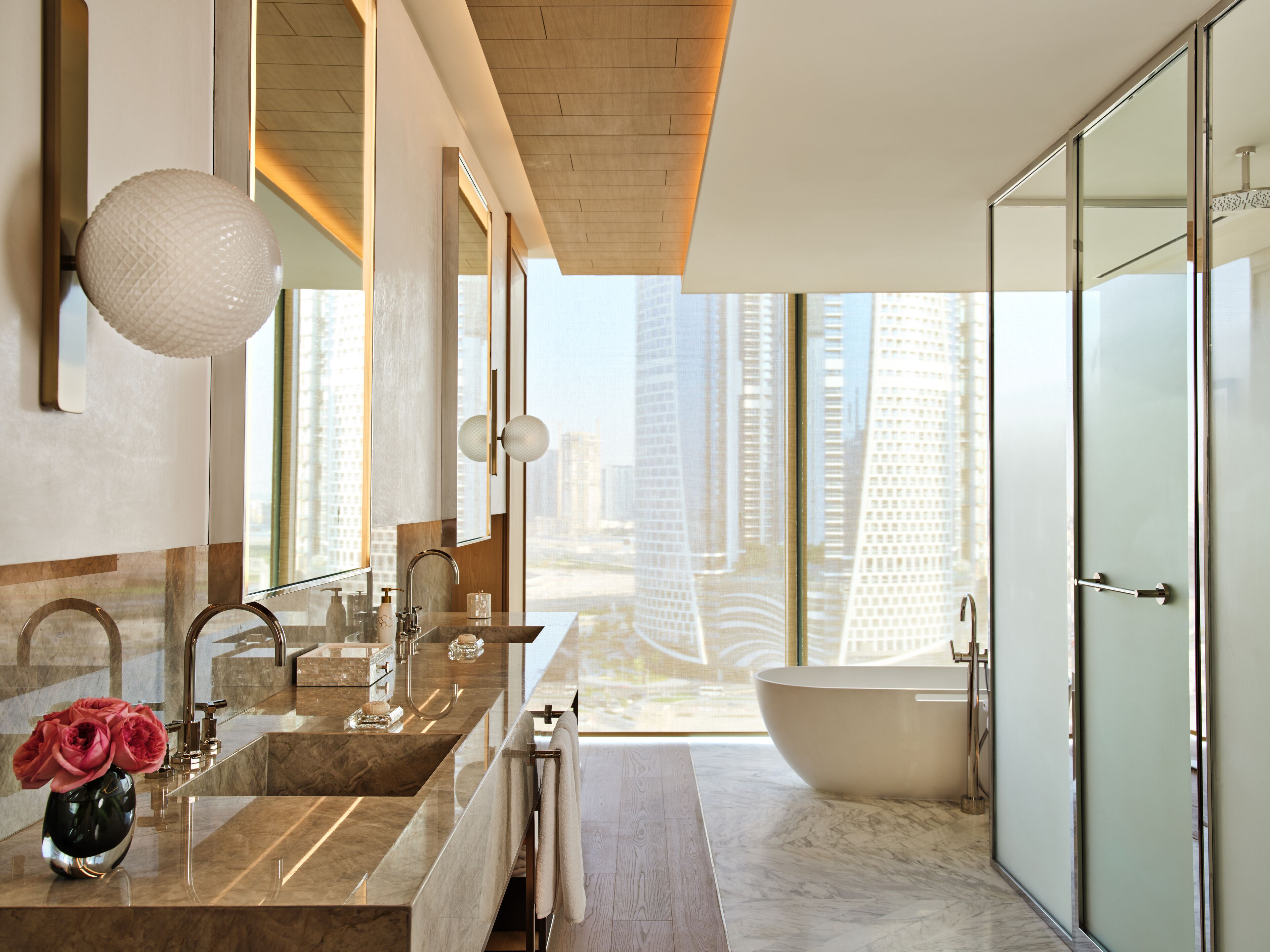 A modern bathroom with a large bathtub, dual sinks, and a large mirror.