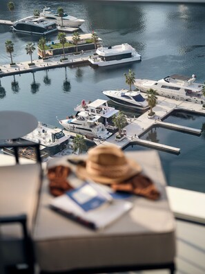 A marina with yachts docked, a view of the water, and a table with a hat and papers.