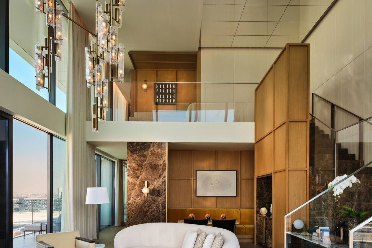 A spacious living area with a white sofa, a round coffee table, and a large window offering a city view.