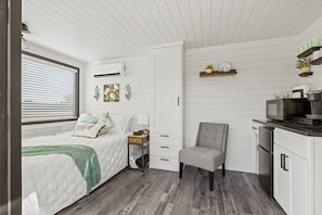A bedroom with a bed, bedside table, lamp, and a chair.