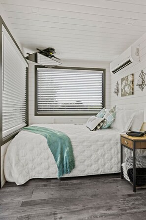 Ein Schlafzimmer mit Bett, Fenster, Nachttisch und Wanddekorationen.