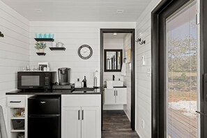 Eine moderne Küche mit Mikrowelle, Kaffeemaschine und einer Uhr an der Wand.