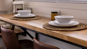 A kitchen with a long countertop, two chairs, and a window with blinds. - New! The Desert Escape-Cozy Container Home (Fredericksburg)