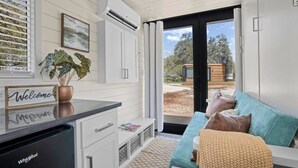 A modern kitchen with a countertop, a dishwasher, and a window with blinds. - New! The Desert Escape-Cozy Container Home (Fredericksburg)
