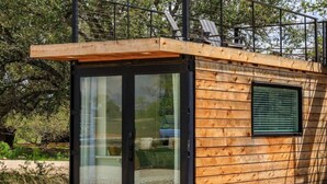 Uma cabana de madeira moderna com porta de entrada de vidro deslizante, uma janela pequena e um deck.