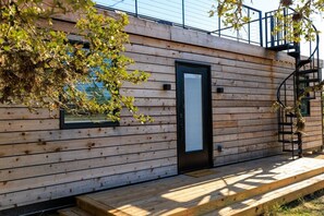 A wooden exterior with a door and window, a wooden deck, and a spiral staircase.