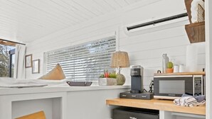 Una cocina compacta con muebles blancos, un lavavajillas negro y una encimera de madera.