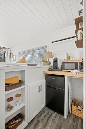 A compact kitchen with white cabinetry, a black dishwasher, and a wooden countertop.