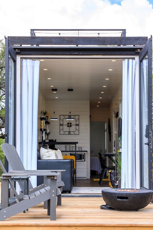 Un espace de vie moderne et compact, comprenant un canapé, une table à manger et un coin cuisine visible à travers une porte ouverte.