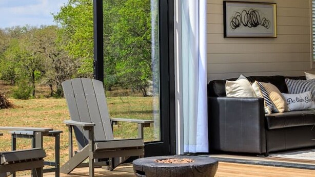Eine offene Terrasse mit Feuerstelle, Sitzgelegenheiten und Blick auf die umliegende Landschaft.