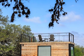 A wooden cabin with a balcony, a chair, and a window.