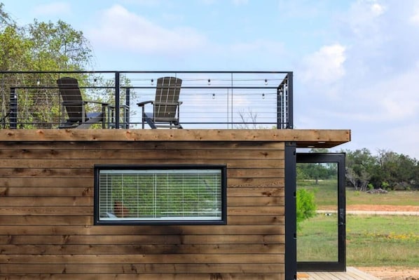 Eine moderne Holz-Blockhütte mit Balkon, zwei Stühlen und einem großen Fenster.