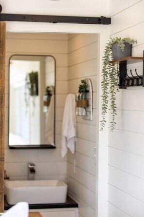 Une salle de bain avec un lavabo blanc, un miroir et une serviette accrochée au mur.