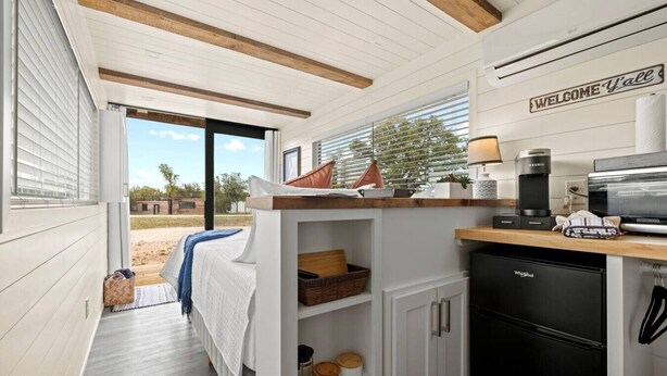 A compact kitchen with a built-in refrigerator, a coffee maker, and a microwave. - New! The Perry-Chic container home Oasis (Fredericksburg)