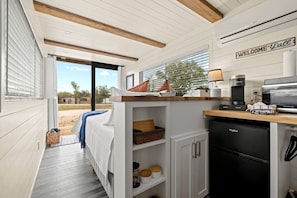 Una cocina compacta con refrigerador, cafetera y microondas integrados.