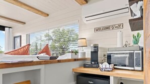 A compact kitchen with white cabinetry, a black dishwasher, a microwave, and a coffee maker. - New! The Perry-Chic container home Oasis (Fredericksburg)