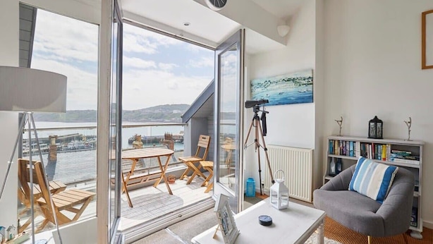 Un salon moderne avec un balcon, un télescope et une bibliothèque.