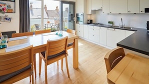 Une cuisine moderne avec des meubles blancs, un plan de travail noir et un coin repas doté de meubles en bois.