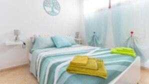 Un dormitorio con cama, almohadas, una mesita de noche y un adorno en la pared.