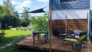 A backyard with a wooden deck, a dining table, chairs, and a barbecue grill. - Gîte du Moulin de Tart le Bas (Tart-le-Bas)