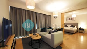 Ein modernes Hotelzimmer mit Sofa, Fernseher, Schreibtisch mit Stuhl und einem Bett.