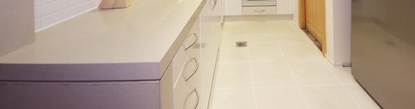 A kitchen with white cabinets, a countertop, and a tiled floor. - Relaxing Condo in Al Raha Beach (Abu Dhabi)
