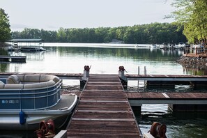 A dock with a hot tub and a boat, surrounded by calm water and trees.