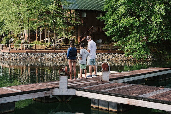 A wooden dock extending into a calm body of water, with a rustic building in the background.