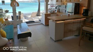 Een moderne keuken met uitzicht op zee, een eethoek met tafel en stoelen, en een bar.