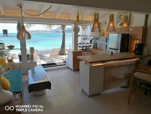 A modern kitchen with a view of the sea, a dining area with a table and chairs, and a bar area. - LOVE BEACH LOFT (Marigot)