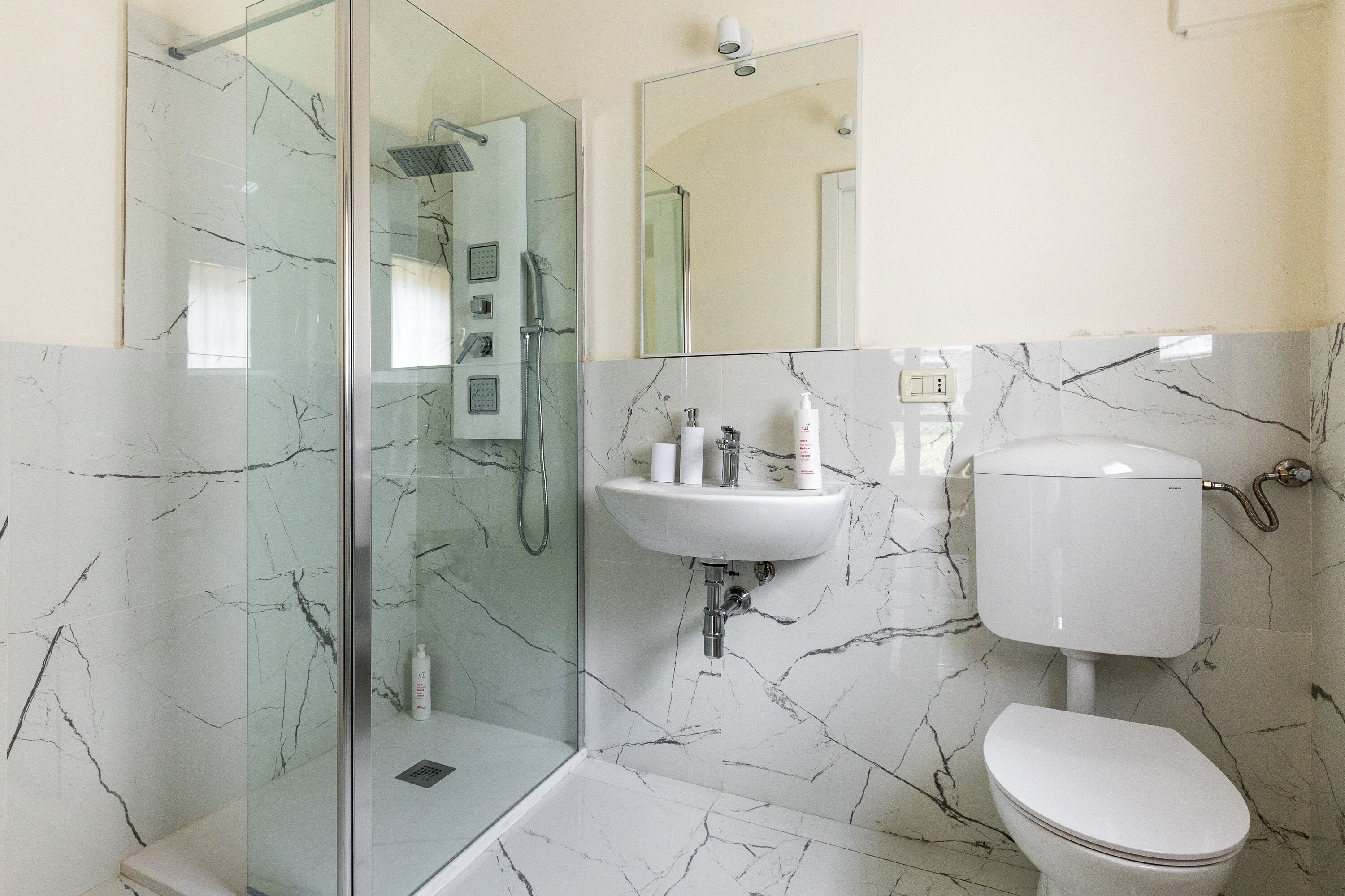 A modern bathroom with a glass-enclosed shower, a white sink, and a toilet.