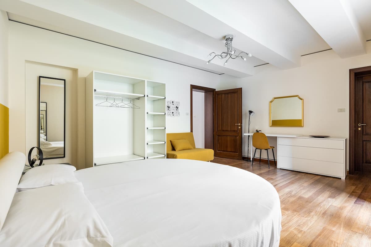Un dormitorio con una cama grande, un armario, un escritorio y una silla.