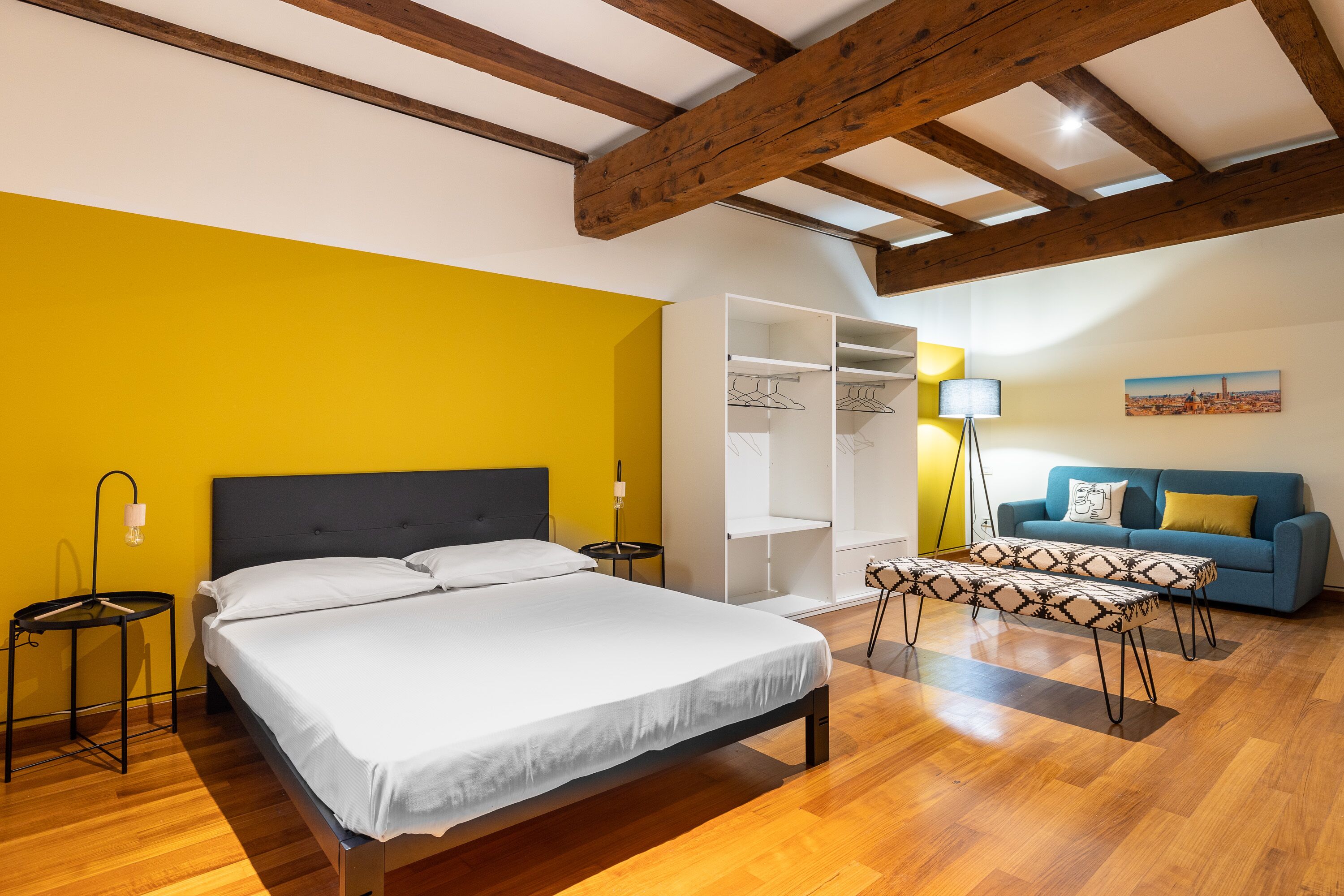 Ein Schlafzimmer mit Bett, Nachttischen, einem Kleiderschrank, einer Bank, einer Couch und einer Lampe.