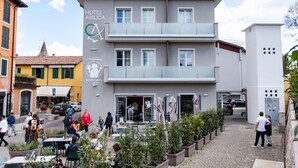 Un hotel de diseño moderno, con una planta baja que incluye mesas al aire libre y un restaurante. El edificio tiene varios pisos y una entrada visible.