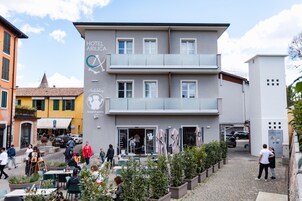 Un hotel de diseño moderno, con una planta baja que incluye mesas al aire libre y un restaurante. El edificio tiene varios pisos y una entrada visible.