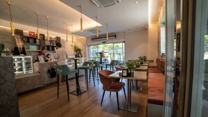 Interior de una cafetería moderna con suelo de madera, taburetes de bar y una barra con una máquina de café.