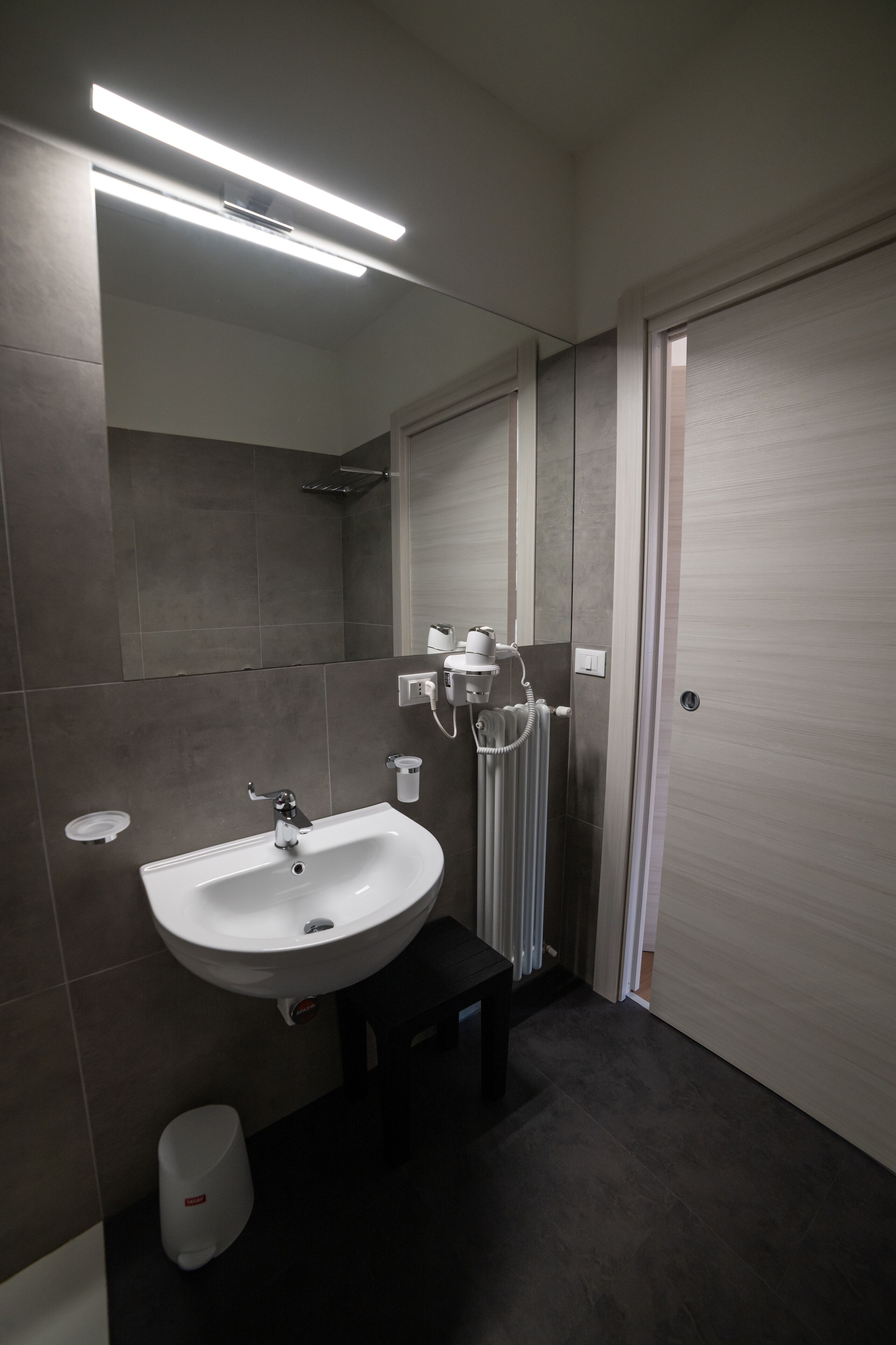 Ein modernes Badezimmer mit einem weißen Waschbecken, einem Spiegel und einer Duschkabine.