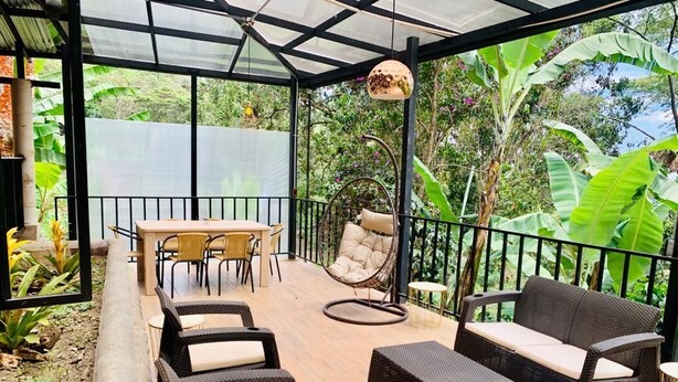 Une terrasse extérieure aménagée avec des meubles en osier, une table et des chaises.