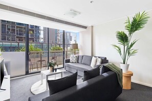 A modern living room with a grey sofa, a coffee table, and a large potted plant.