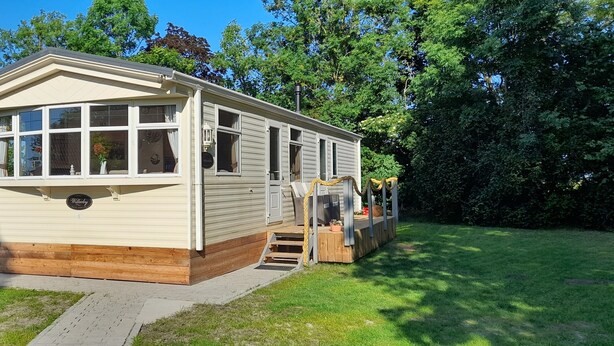 A mobile home with a porch, a small deck, and a front entrance.