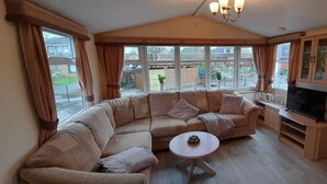 A cozy living room with a large L-shaped sofa, a small round coffee table, a flat-screen TV, and a fireplace.