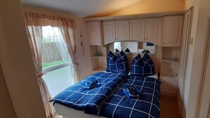 A bedroom with a bed, a nightstand, and a window with curtains.